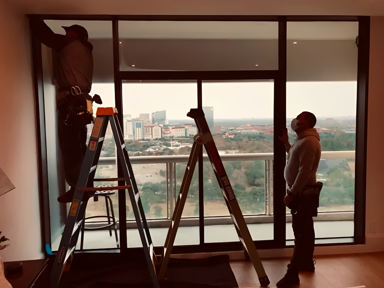 Two men fixing window with city view