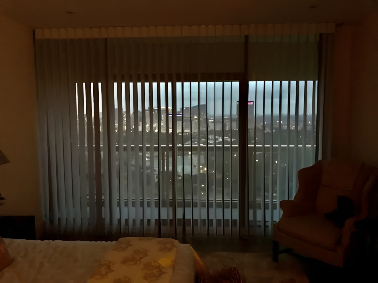Cityscape view through vertical blinds at dusk