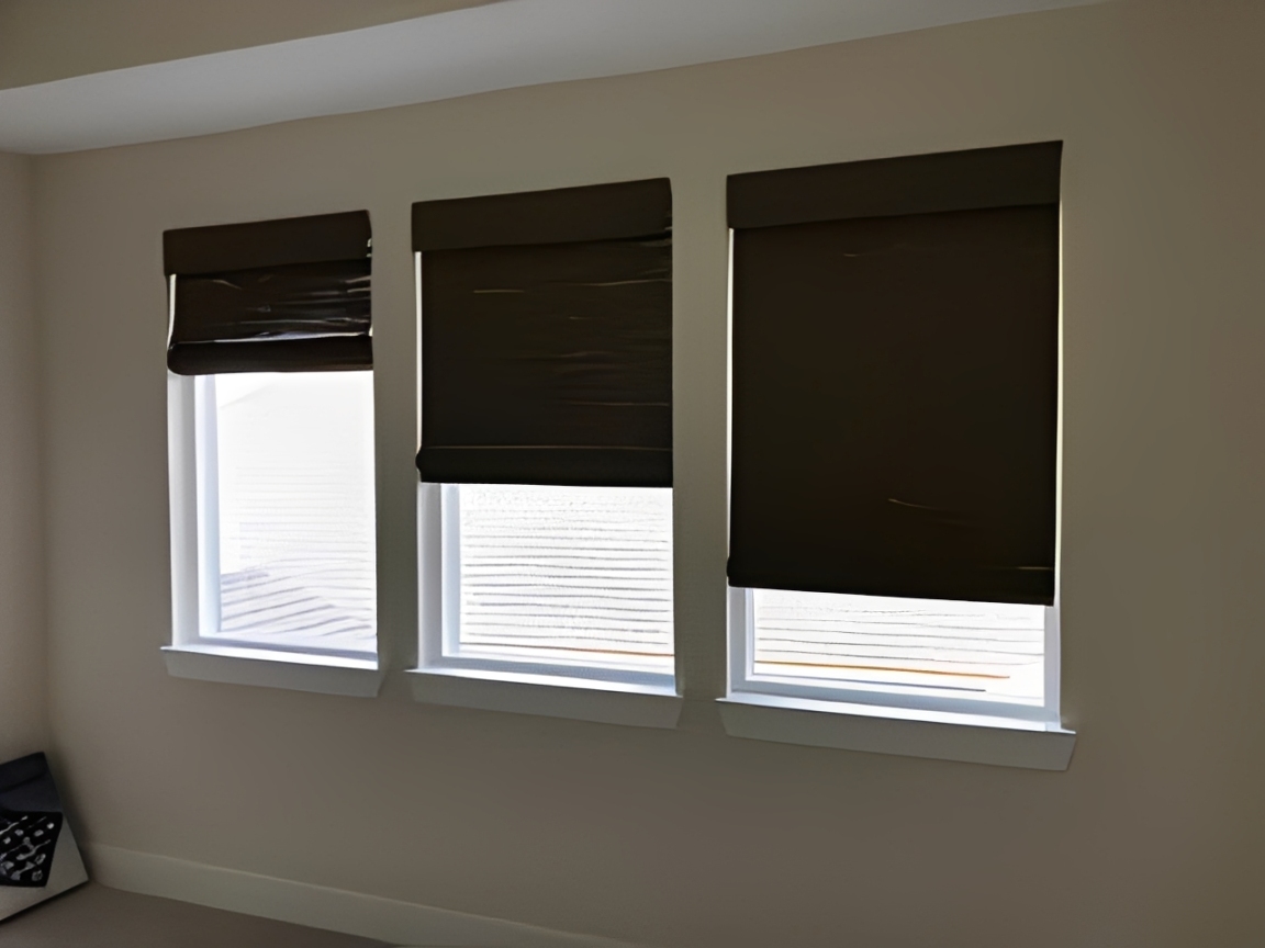 Three windows with brown blinds partially open.